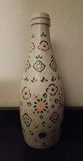 A white glass bottle with a hand-painted folk-art pattern in green and orange.