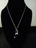A gold-toned chain necklace with a small black and white cat pendant, displayed on a black velvet mannequin bust.