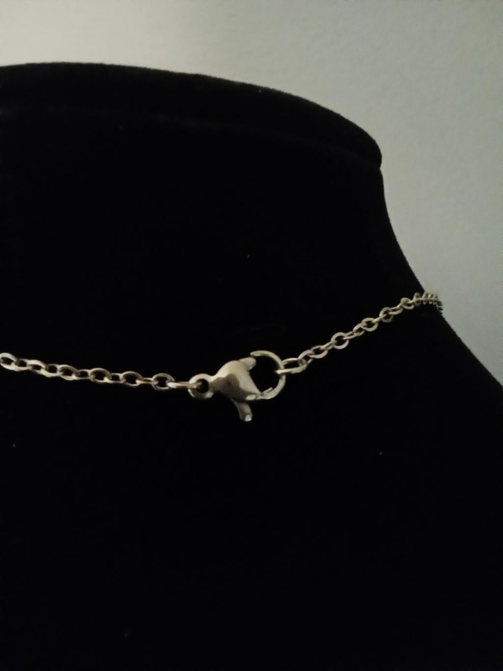 A gold chain necklace with a lobster clasp, displayed on a black velvet jewelry bust.