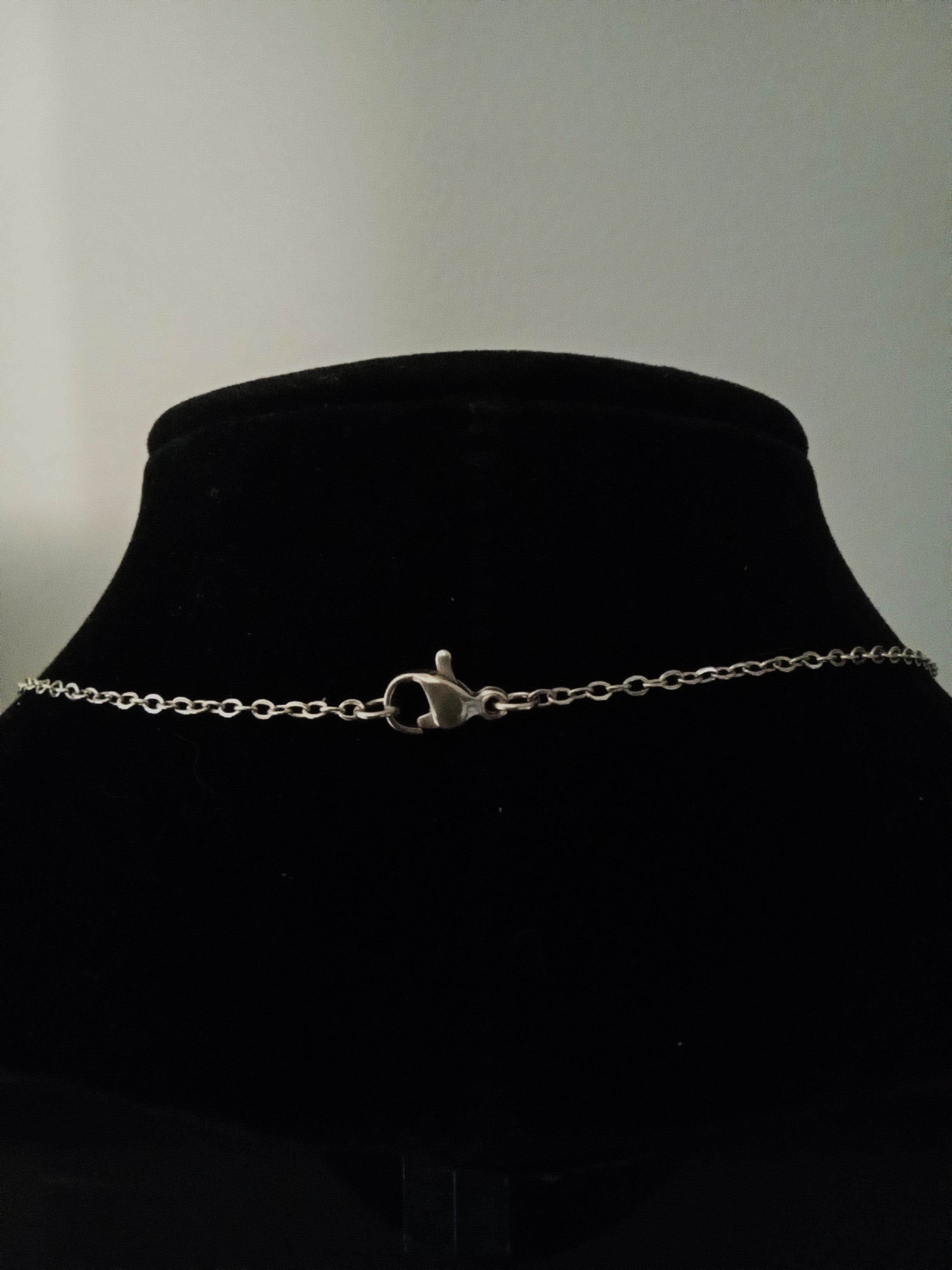 A gold chain necklace with a lobster clasp, displayed on a black velvet jewelry bust.