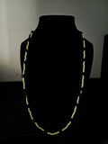 A long, beaded necklace displayed on a black mannequin bust against a dark background. The necklace features alternating dark navy blue and yellow beads.