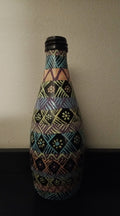 A decorative bottle covered in a colorful geometric tribal-style pattern of blue, yellow, pink, green, and orange.